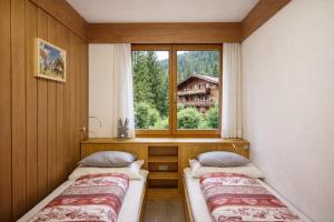 two beds in a room with a window at CASA 4 PIOPPI - Vista Lagorai e tranquillità a Cavalese - Dolomiti Affitti in Cavalese