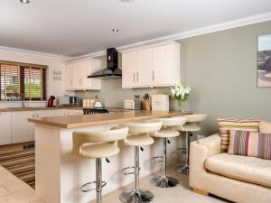 a kitchen with white cabinets and a bar with stools at 4 Bed in Ystradgynlais oc-bn343 in Ystalyfera +13 photos