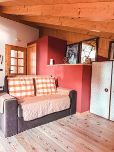 a couch in a room with a red wall at Mansarda Il Castello in Ossana