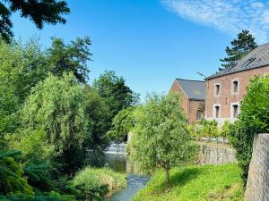a river in front of a brick building and a building at Moulin de Meeffe in Wasseiges