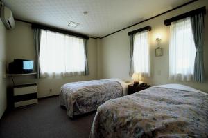 um quarto de hotel com duas camas e uma televisão em Hill Top em Kiso