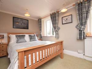 a bedroom with a wooden bed and two windows at 4 Bed in Barnstaple oc-73949 in Stoke Rivers