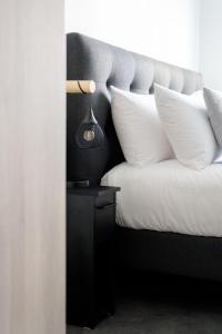 a bed with white pillows and a lamp on a table at SLO HOSTEL Bordeaux in Bordeaux