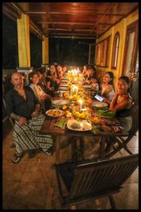 a group of people sitting around a long table at Camplung Beach Family Villa and Farmstead in Tejakula