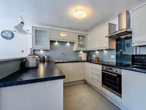 a kitchen with white cabinets and black counter tops at 2 Bed in Woolacombe oc-bkers in Woolacombe