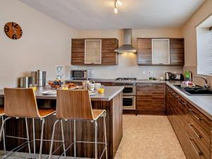 a kitchen with wooden cabinets and a counter with bar stools at 3 Bed in Brecon oc-bn304 in Brecon
