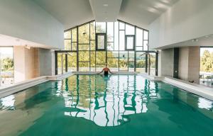 a woman is sitting in a swimming pool with a window at Thermal Hotel Balance Lenti in Lenti
