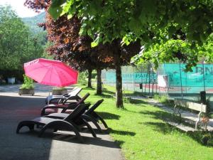 a row of park benches with a pink umbrella at Camping Le SIGNAL Nantua in Nantua