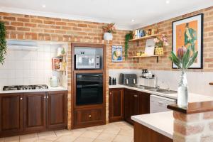 a kitchen with wooden cabinets and a brick wall at Infinity Views in Utakarra