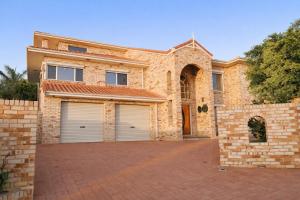 a brick house with two garage doors and a driveway at Infinity Views in Utakarra