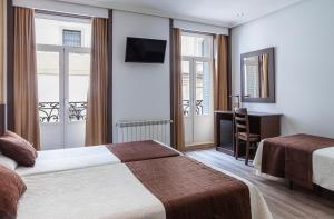 a hotel room with two beds and a desk at Hotel Mediodia in Madrid
