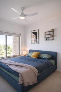 a bedroom with a blue bed with a ceiling fan at Infinity Views in Utakarra