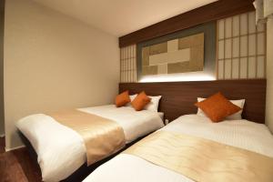 two beds in a hotel room with at KURASHIKI Station HOTEL 和奏 in Kurashiki
