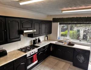 a kitchen with black cabinets and a stove and a window at 5 Bedroom house Doncaster in Balby