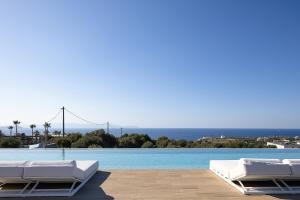 a pool with two white lounge chairs and the ocean at Oliva D'oro Villa - Sunset Gaze by etouri in Chania