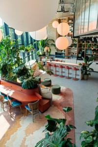 une bibliothèque avec des tables, des chaises et des plantes. dans l'établissement Cocoon München Theresienwiese, à Munich