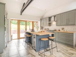 a kitchen with gray cabinets and a island with bar stools at 3 Bed in Brecon oc-92320 in Llandeilor-Fan