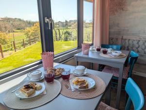 two tables with plates of food in a room with a window at La Sosta del Cardinale in Montefiascone