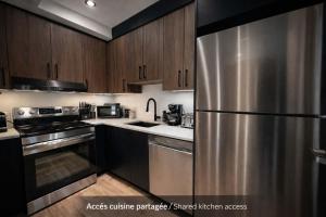 a kitchen with stainless steel appliances and wooden cabinets at Room with a King-Size Bed Downtown Quebec in Quebec City