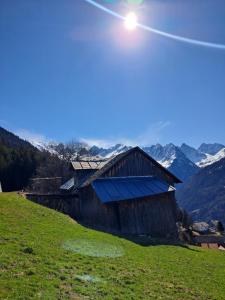 an old barn on a hill with mountains in the background at Hof am Berg in Kaunerberg