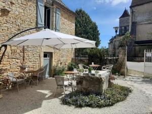 a patio with an umbrella and a table and chairs at La P'tite Place in Les Arques