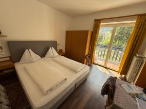a bedroom with a white bed with a large window at Garni Franz Leiter in Lagundo +36 photos