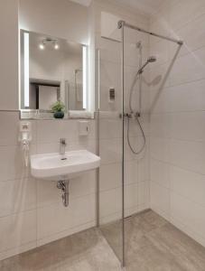 ein weißes Badezimmer mit Waschbecken und Dusche in der Unterkunft Amper Art Hotel in Fürstenfeldbruck + 22 Fotos