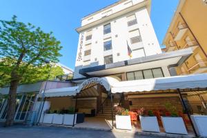 a large white building with an archway in front of it at MH Hotel Maracaibo in Rimini