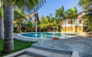 a swimming pool in front of a house with palm trees at Savannah Bstan Luxury Apartment in Diani Beach