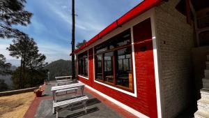a red and white building with two benches outside at Hidden Mountain Resort in Almora +23 photos