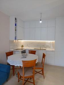 a white kitchen with a table and chairs and a sink at Amaris-Kian Tragaj Apparent in Vlorë +4 photos