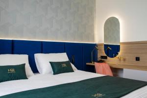 a bedroom with a bed with green and white pillows at Boutique Hotel H23 in Pezinok