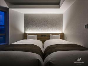 two beds sitting next to each other in a bedroom at Daiwa Roynet Hotel Nagoya Eki Mae in Nagoya
