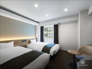 a hotel room with two beds and a chair at Daiwa Roynet Hotel Nagoya Eki Mae in Nagoya +63 photos