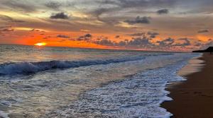 a sunset on a beach with the ocean and the waves at Amazing beach apartment Phuket in Phuket