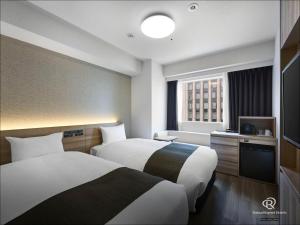 a hotel room with two beds and a television at Daiwa Roynet Hotel Nagoya Eki Mae in Nagoya