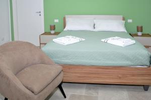 a bedroom with a bed and a chair with towels on it at Villa Luce Relax by Perle di Puglia in Villa Castelli +21 photos