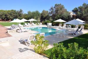 a pool with white chairs and tables and umbrellas at Villa Luce Relax by Perle di Puglia in Villa Castelli