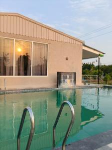 a swimming pool in front of a building at Cherish Farm Stay in Medchal