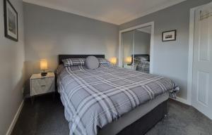 a bedroom with a bed with a plaid blanket and a mirror at Dunuaran in Oban