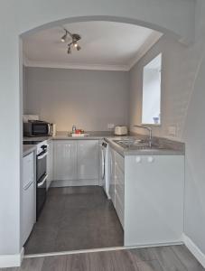 a kitchen with white cabinets and a ceiling fan at Dunuaran in Oban