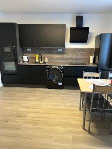 a kitchen with black cabinets and a table and a dishwasher at Na Písku in Most +3 photos