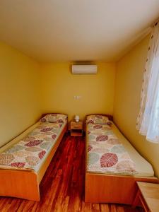 two beds in a room with yellow walls and wooden floors at Apartment and Room Natasa in Kobarid