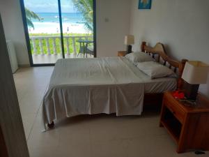 a bedroom with a bed with a view of the ocean at Rosemary's Guesthouse in Praslin