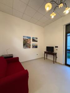 a living room with a red couch and a desk at Guest House Colfiorito by Ospitaci in Colfiorito