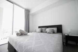 a white bedroom with a large bed and a window at Rooftop Apartment - Heated Pool & Beach access in Marcoola