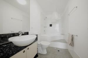 a white bathroom with a sink and a toilet at Rooftop Apartment - Heated Pool & Beach access in Marcoola
