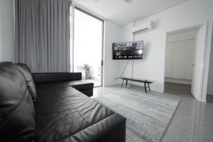 a living room with a leather couch and a tv at Rooftop Apartment - Heated Pool & Beach access in Marcoola