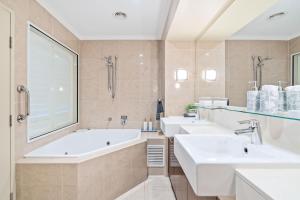 a bathroom with three sinks and a tub at Oceanfront Spa Suite - Sub Penthouse in Urangan