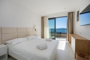 a bedroom with a white bed with a view of the ocean at Wind Rose Maestral-beachfront in Igrane +59 photos